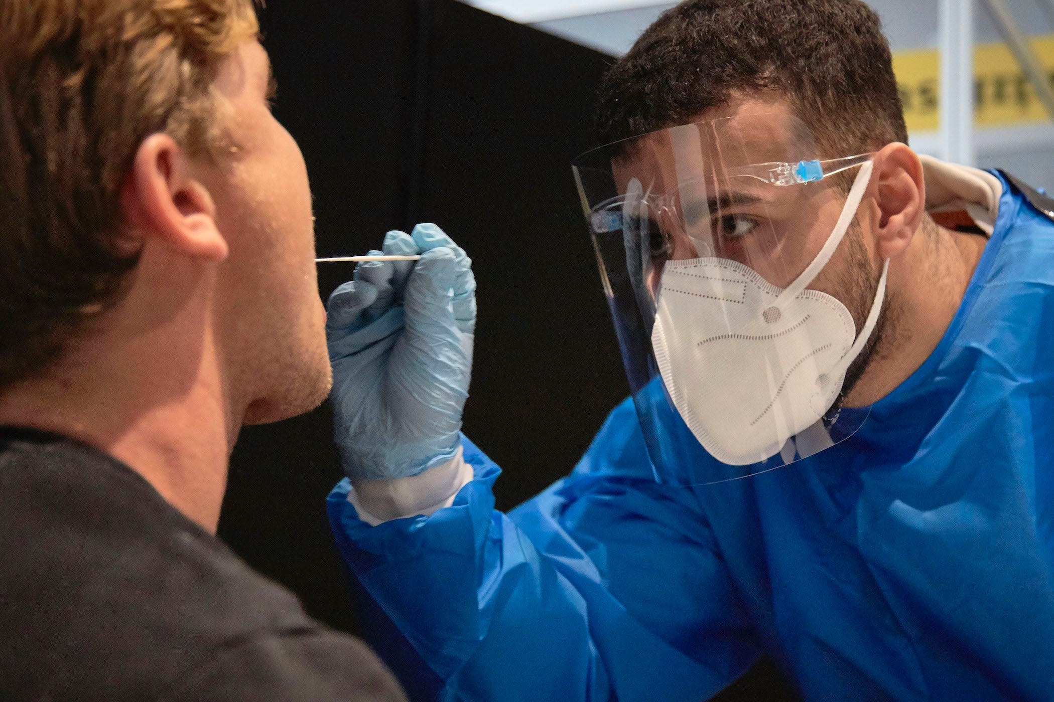 passenger from south africa flight getting tested by man in mask and shield swabbing his nose