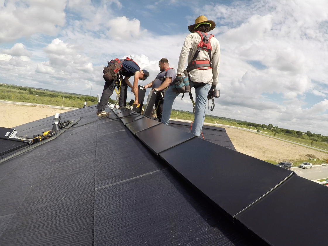 Workers installing a Tesla Solar Roof on a home in the SunHouse at Easton Park community.