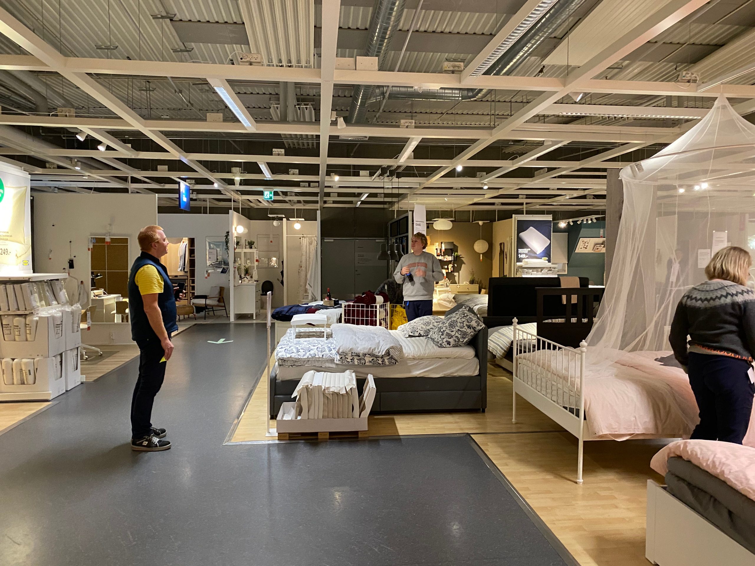 Peter Elmose (L) looks on as customers and employees choose beds to sleep in the IKEA showroom.