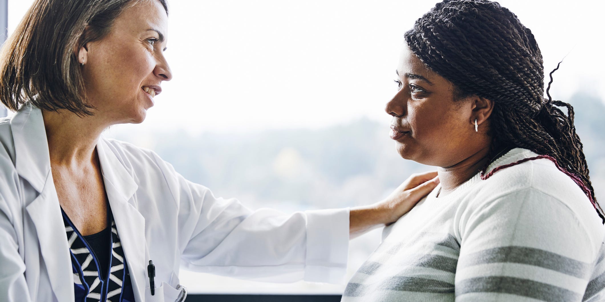 A woman speaks to another woman in a doctor's office setting.