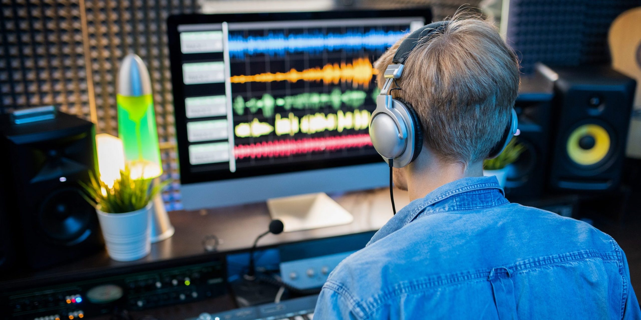 A man sitting at a computer editing audio and music.