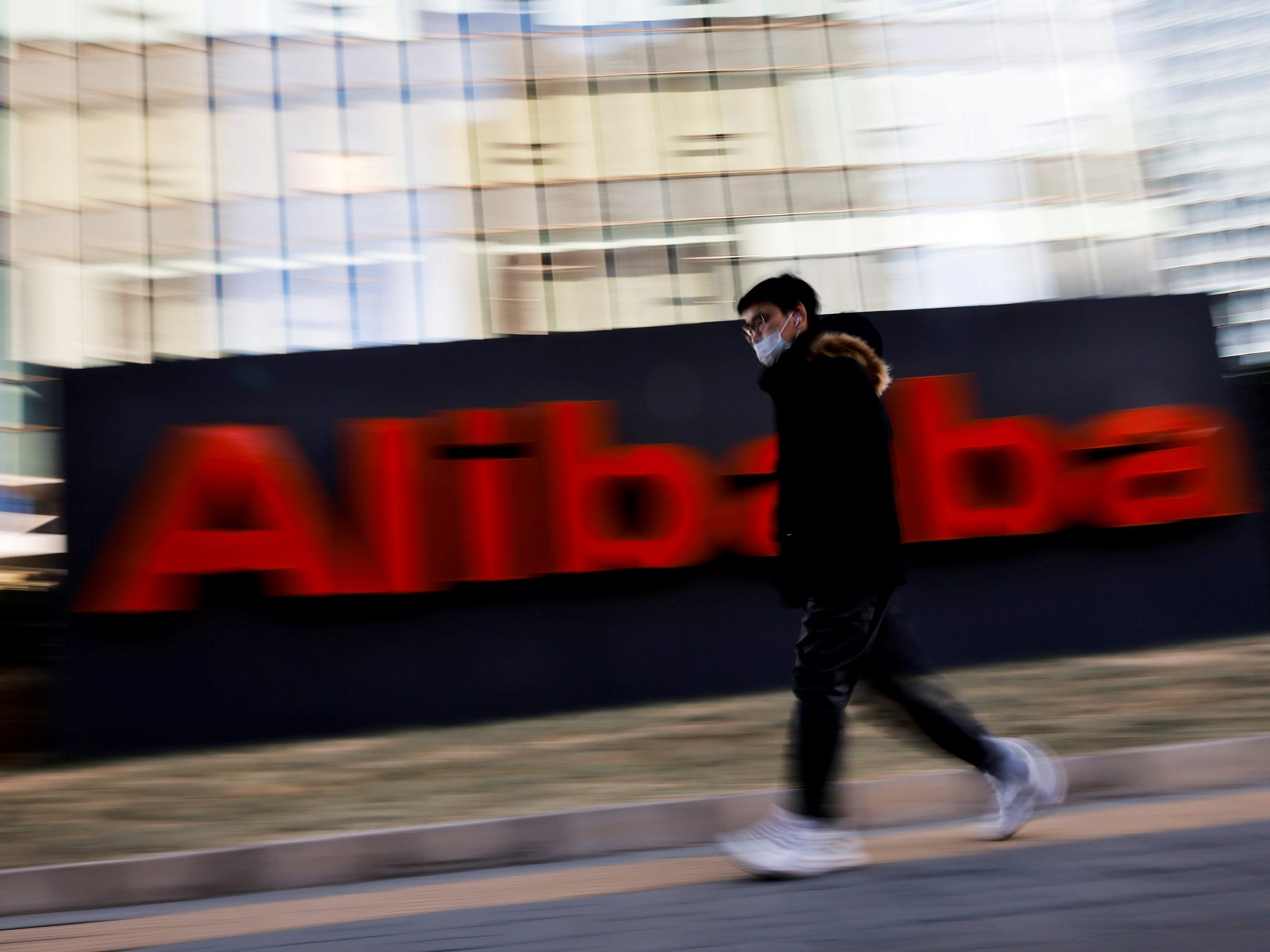 man walks past alibaba logo at headquarters
