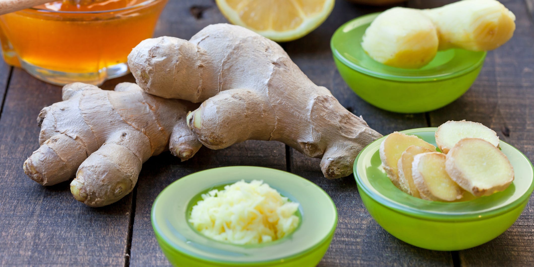 Two large pieces of ginger surrounded by small bowls of peeled ginger, sliced ginger, and grated ginger