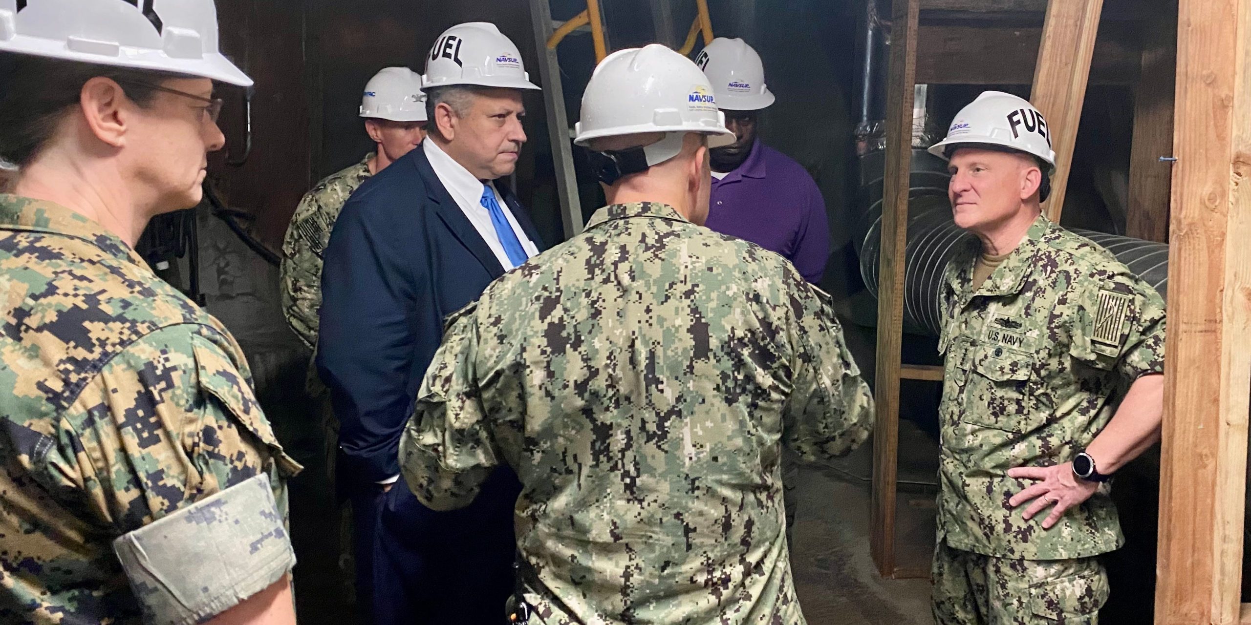 Secretary of the Navy stands with Chief of Navy operations wearing hard hats