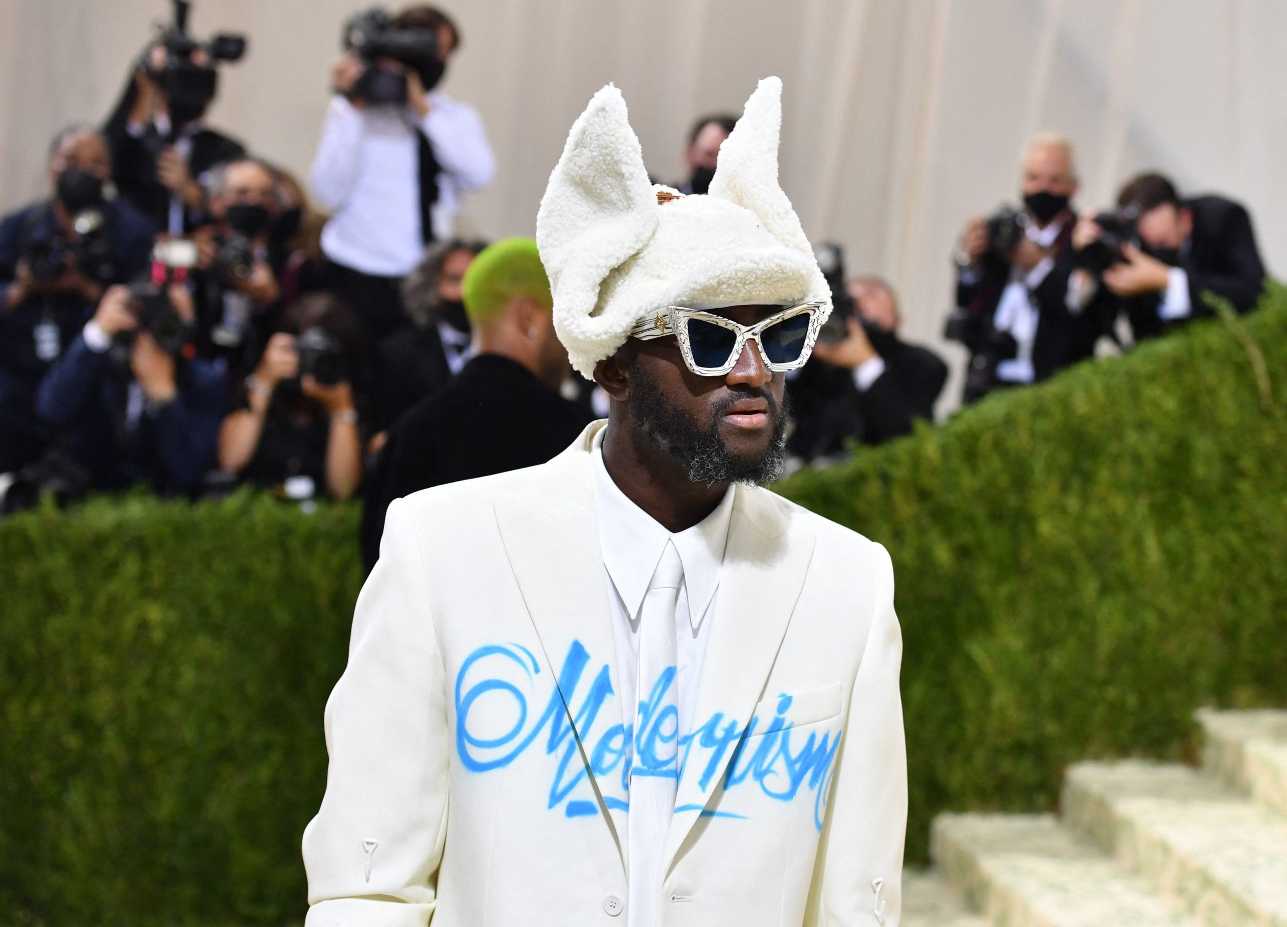 A man. wears a white suit with the word "Modernism" written across it.