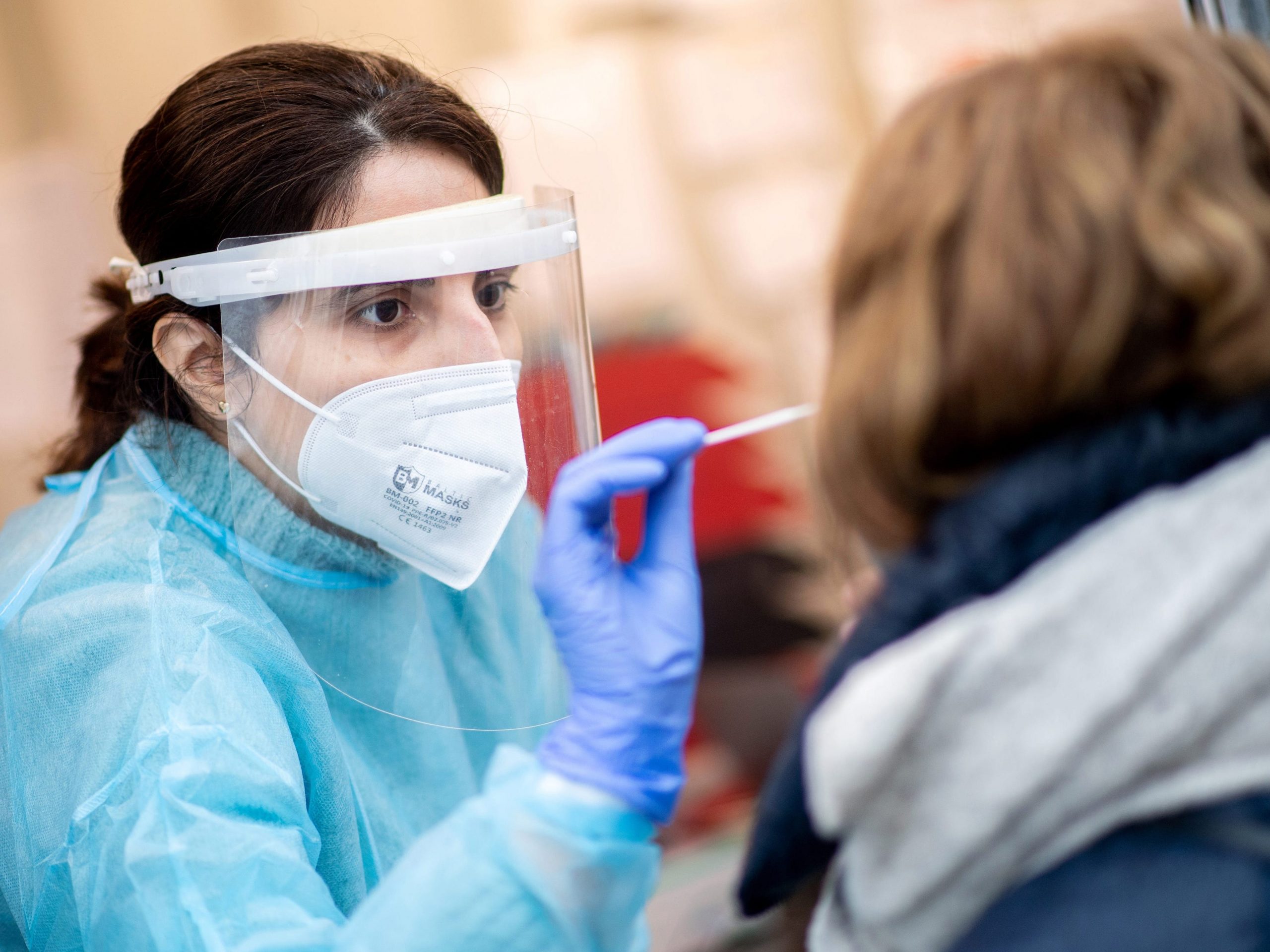 Women with face mask and shield does swab to test for COVID-19.