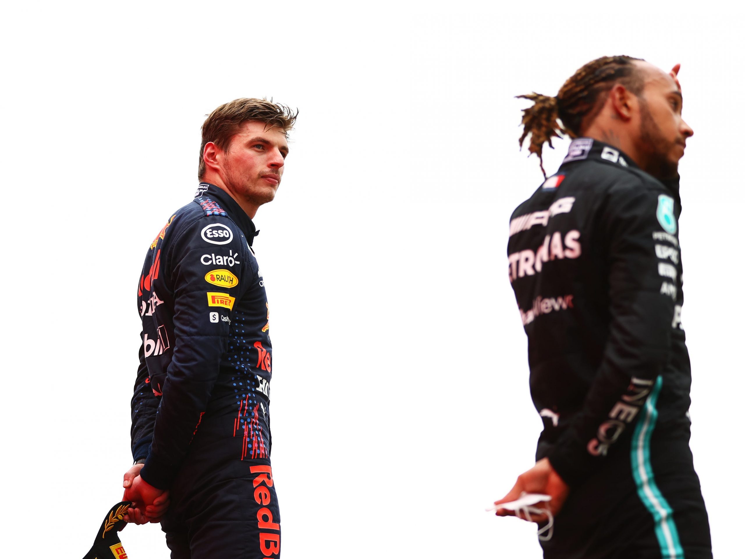 Max Verstappen looks at Lewis Hamilton from the winner's podium.