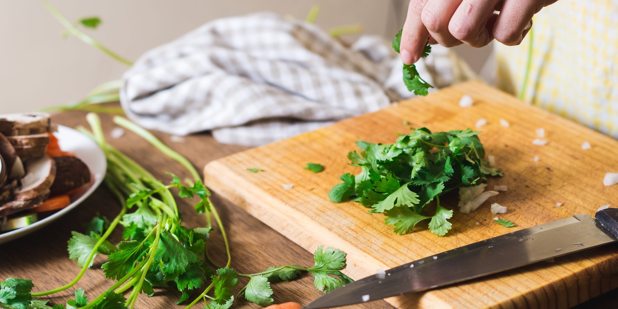 Someone chopping cilantro on a cutting board.