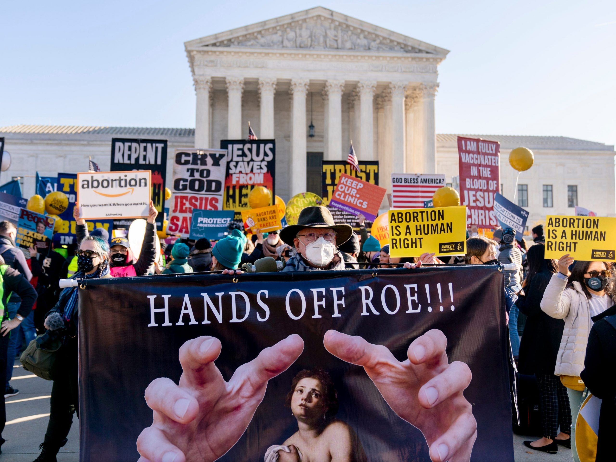 Stephen Parlato of Boulder, Colo., holds a sign that reads "Hands Off Roe!!!" as abortion rights advocates and anti-abortion protesters demonstrate in front of the U.S. Supreme Court, Wednesday, Dec. 1, 2021, in Washington, as the court hears arguments in a case from Mississippi, where a 2018 law would ban abortions after 15 weeks of pregnancy, well before viability.