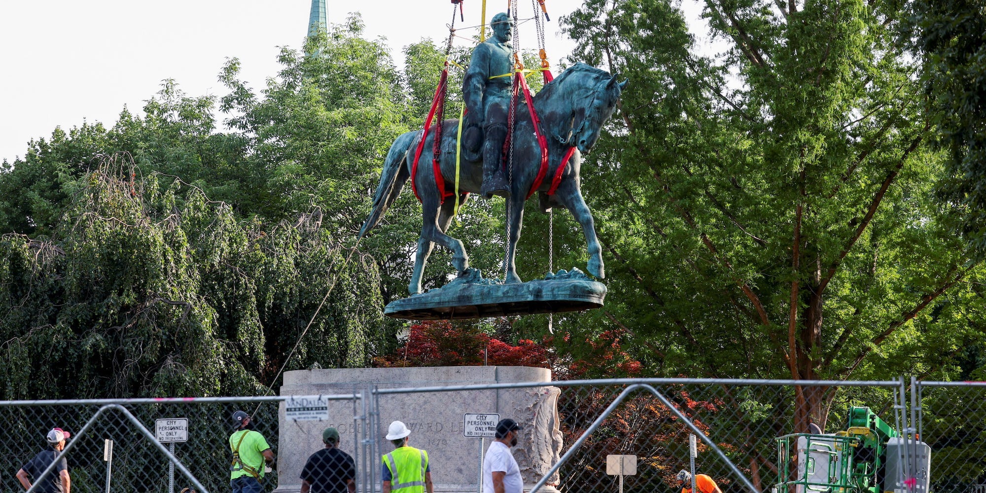 Workers look as a Robert E. Lee statue is held up with straps as it is removed