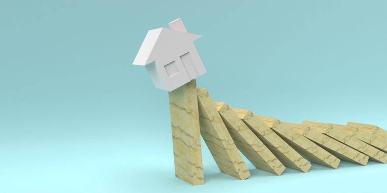 An illustration of a house teetering on the last domino about to fall.