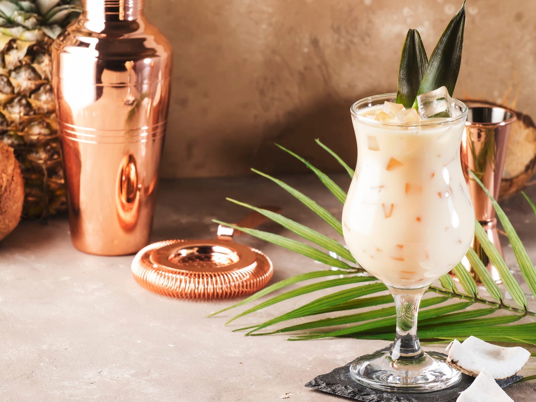 A pina colada or chi chi cocktail in a glass over ice garnished with pineapple leaves