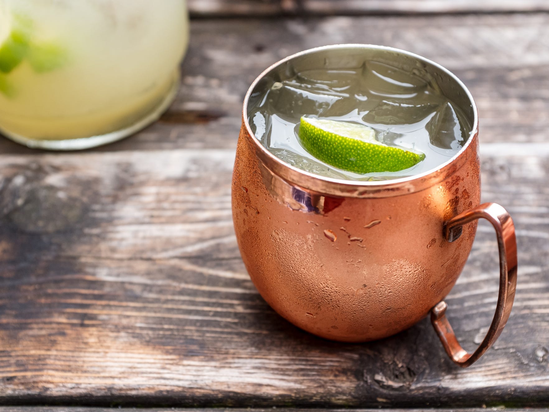 A Moscow mule in a copper mug on a wooden table