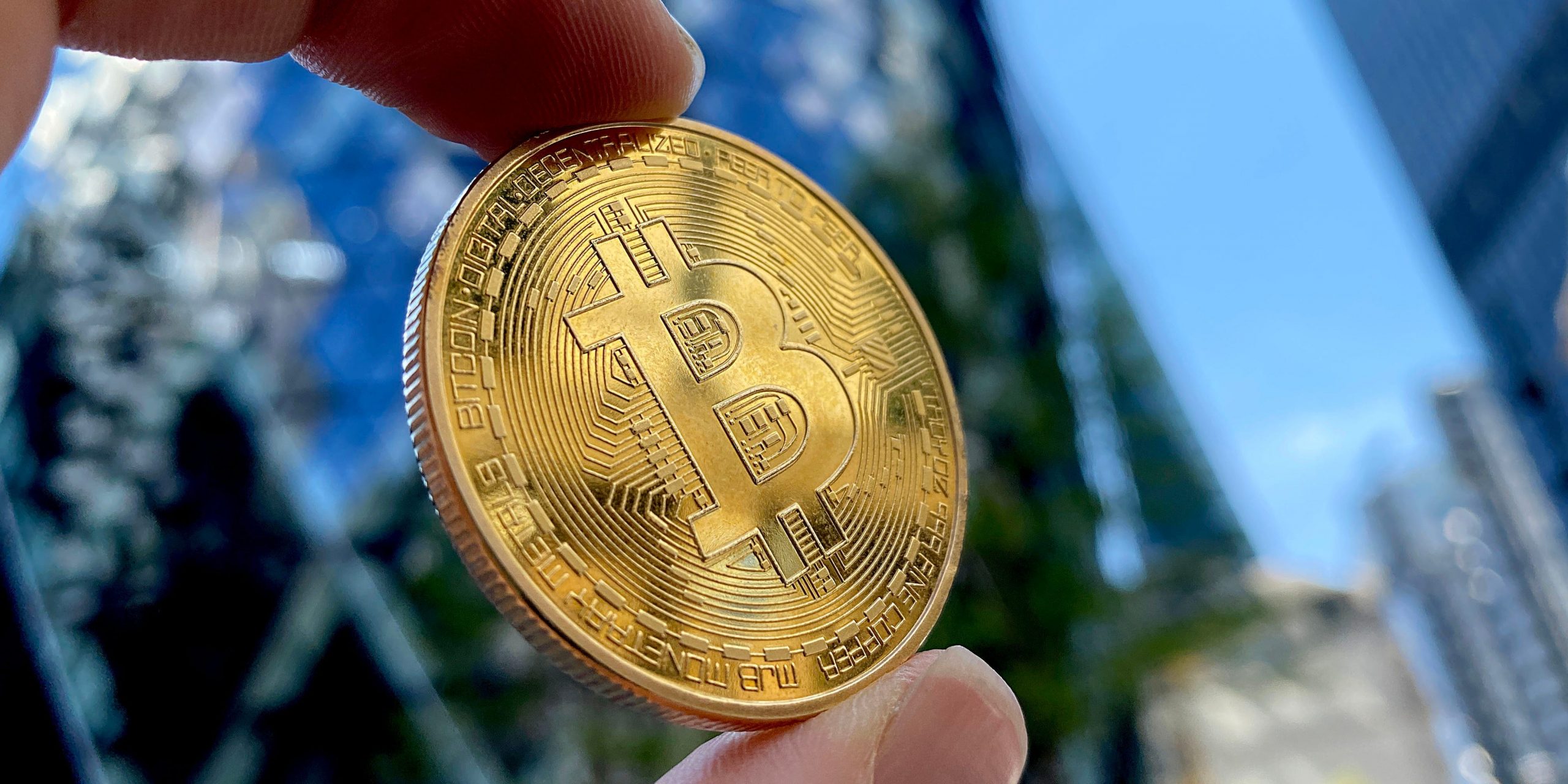 A hand holds a bitcoin toward the sky in this photo representation of the cryptocurrency.