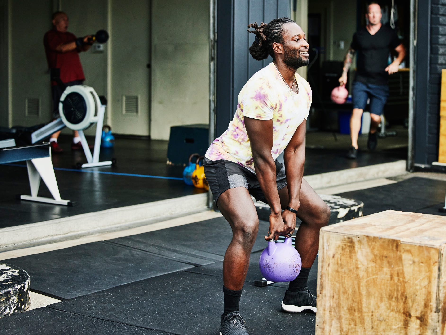 an athlete working out in an outdoor gym with a kettlebell, plyo box, and rower