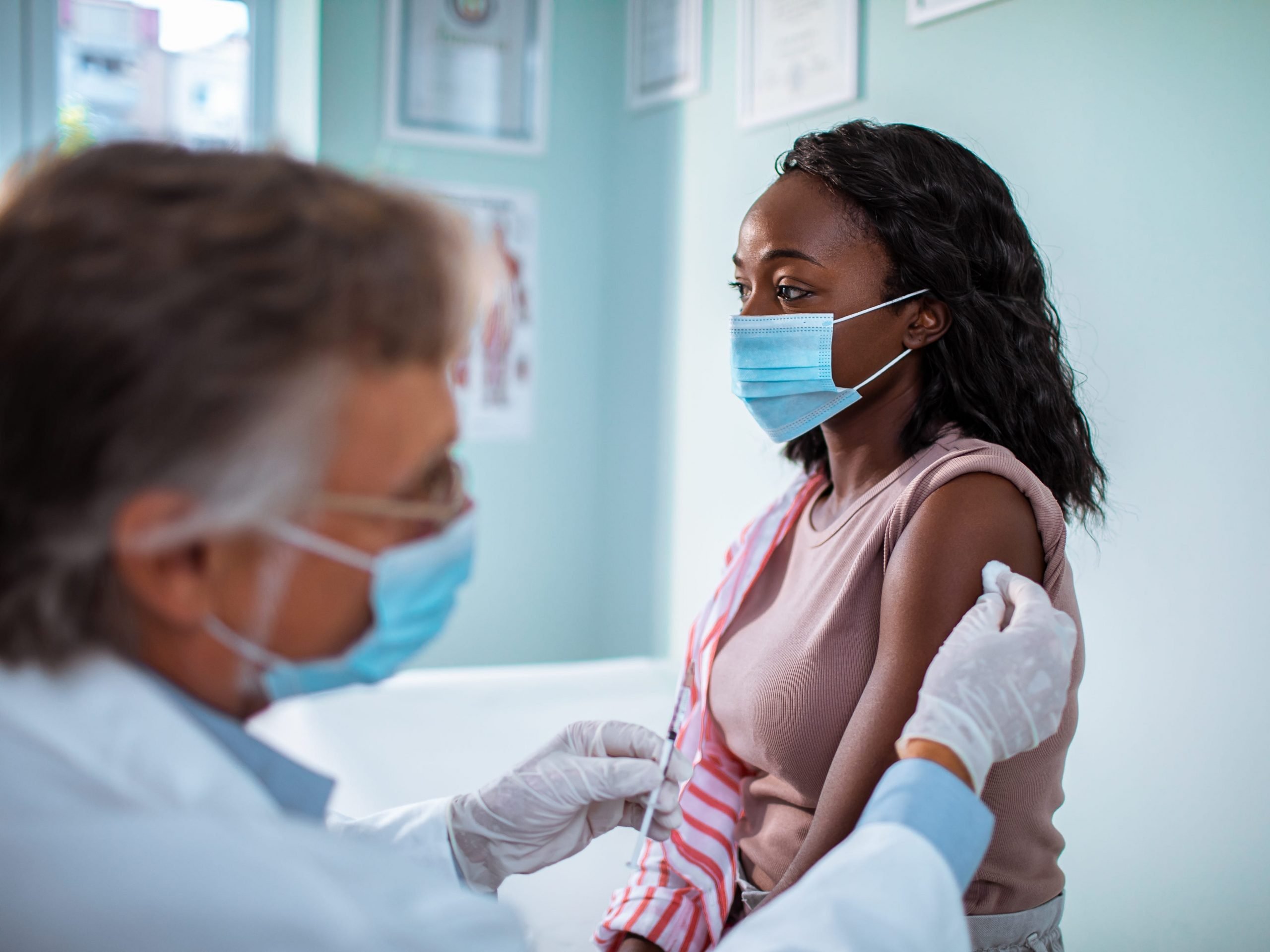 Masked woman receiving vaccine shot.