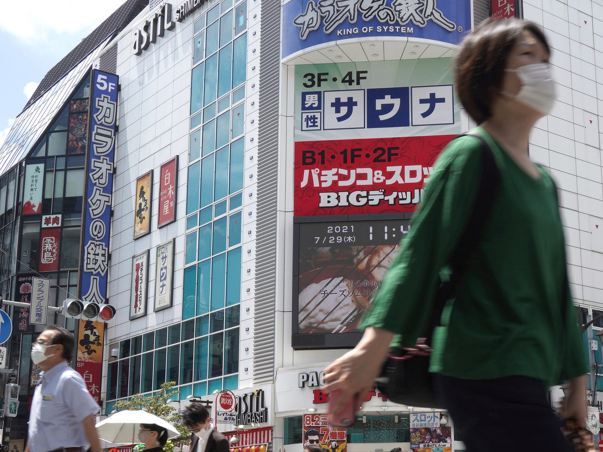 People walk across a crossing near Shimbashi Station in Tokyo Thursday, July 29, 2021.