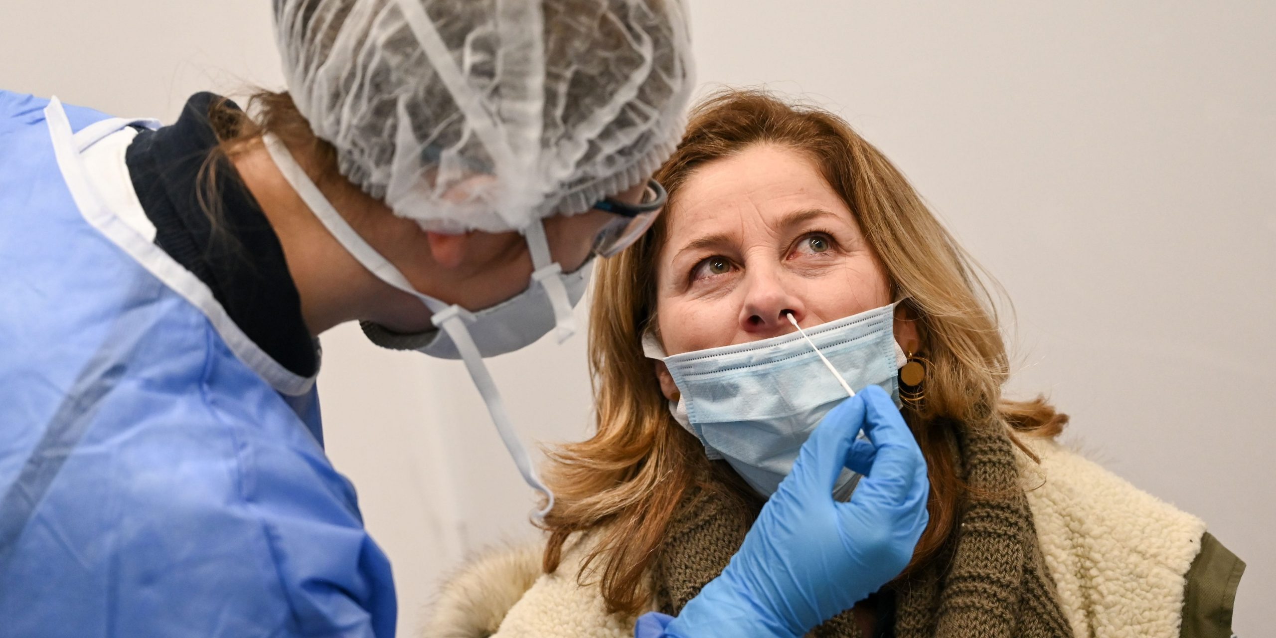 A medical worker wears personal protective equipment (PPE) as she uses a swab to perform a diagnostic PCR test for coronavirus (Covid-19) on an arriving passenger at a testing booth in Roissy-Charles de Gaulle Airport, north-east of Paris on February 13, 2021