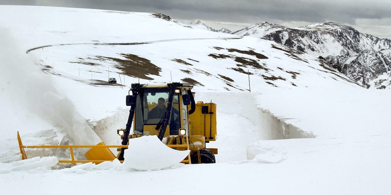 A person uses a snowplow to clear away snow along Trail Ridge Road in Rocky Mountain National Park.