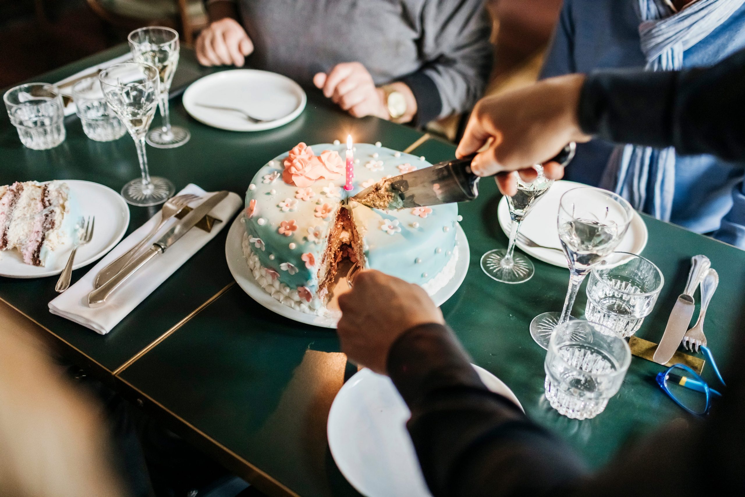 piece being cut from a birthday cake on a platter