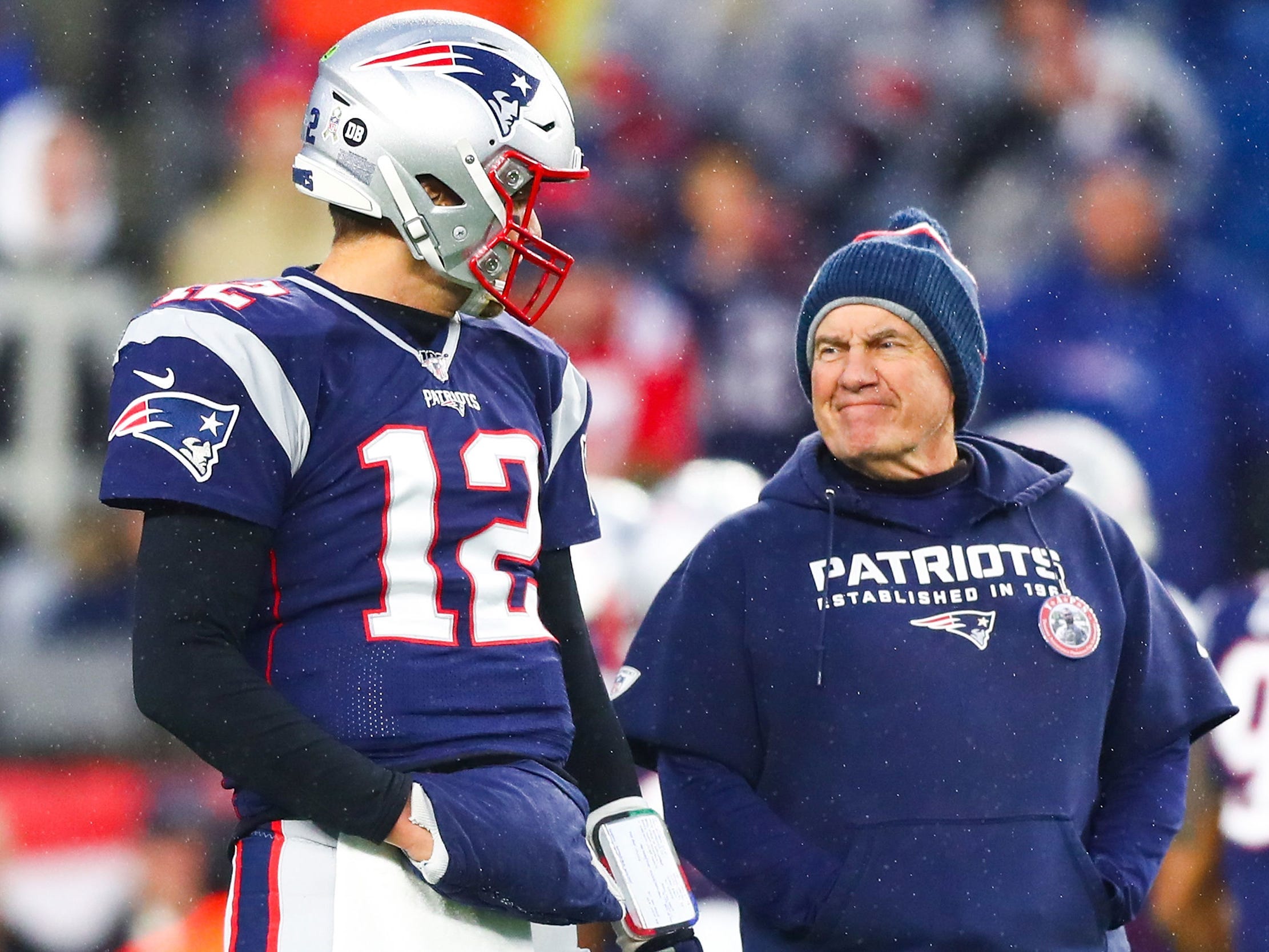 Tom Brady and Bill Belichick stand together on the sidelines ahead of a game in 2019.