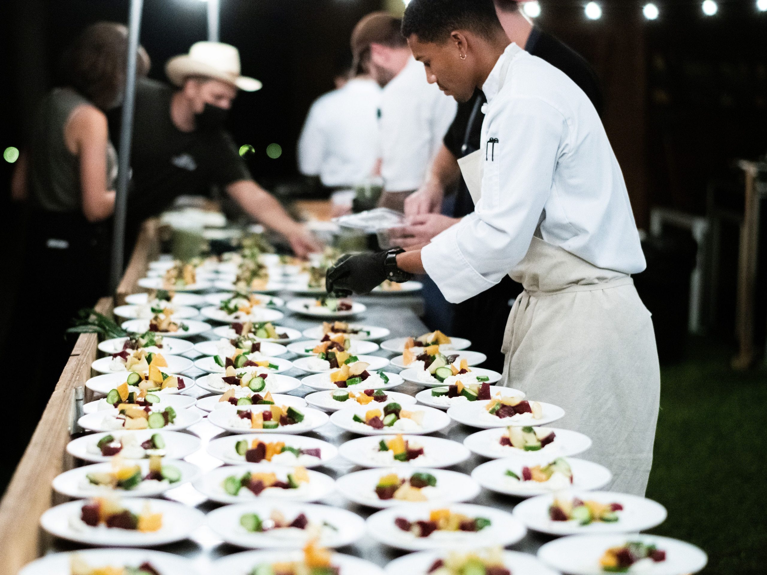 Waiter in white standing over dishes to be served