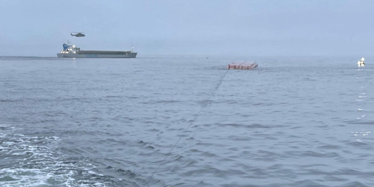 Cargo ship MV Scot Carrier viewed in the distance from the deck of a rescue vehicle