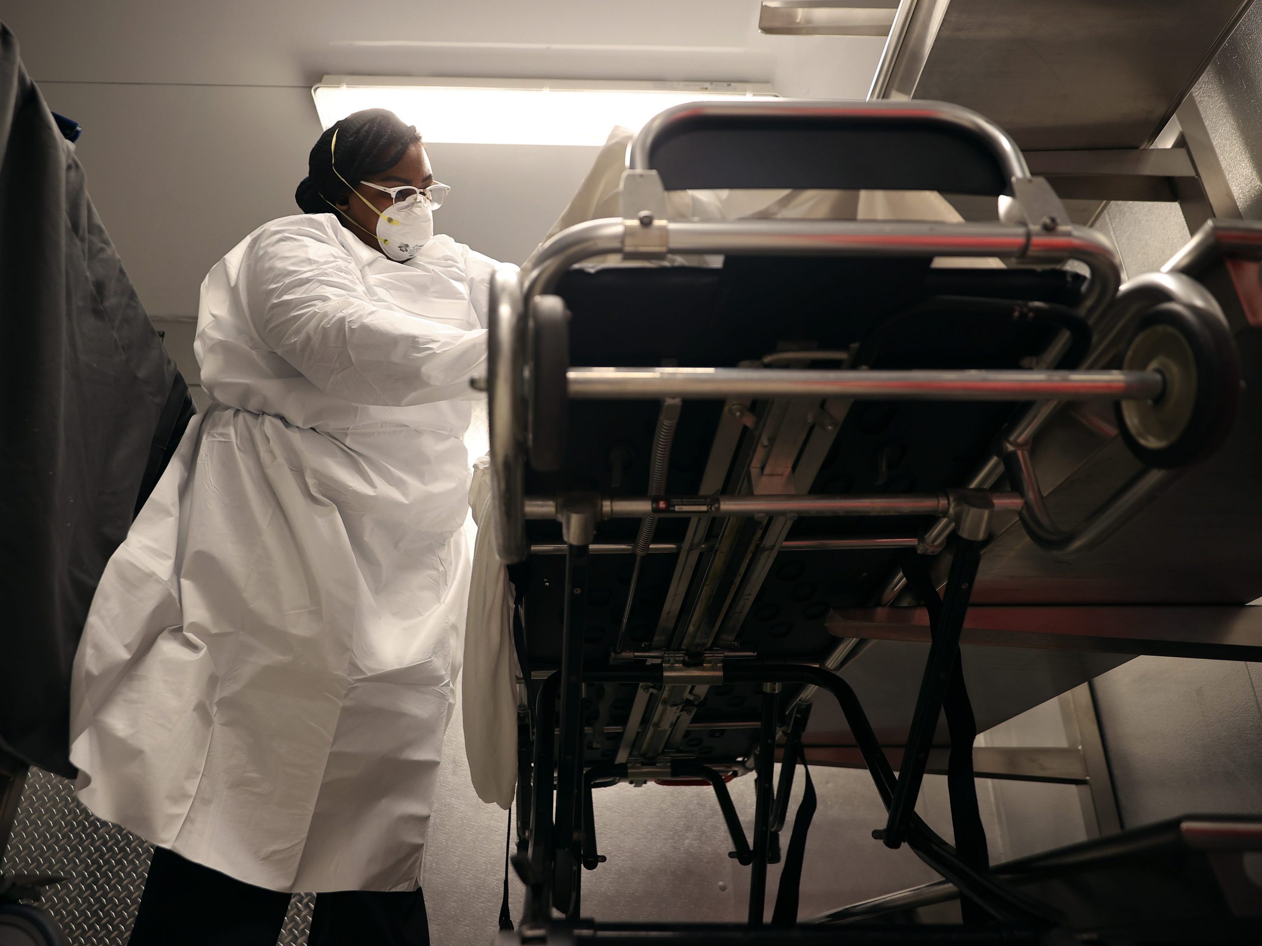 Maryland Cremation Services transporter Morgan Dean-McMillan gently inspects the remains of a coronavirus victim to triple check identification and look for personal belongings in the morgue at Adventist HealthCare White Oak Medical Center May 11, 2020 in Silver Spring, Maryland.