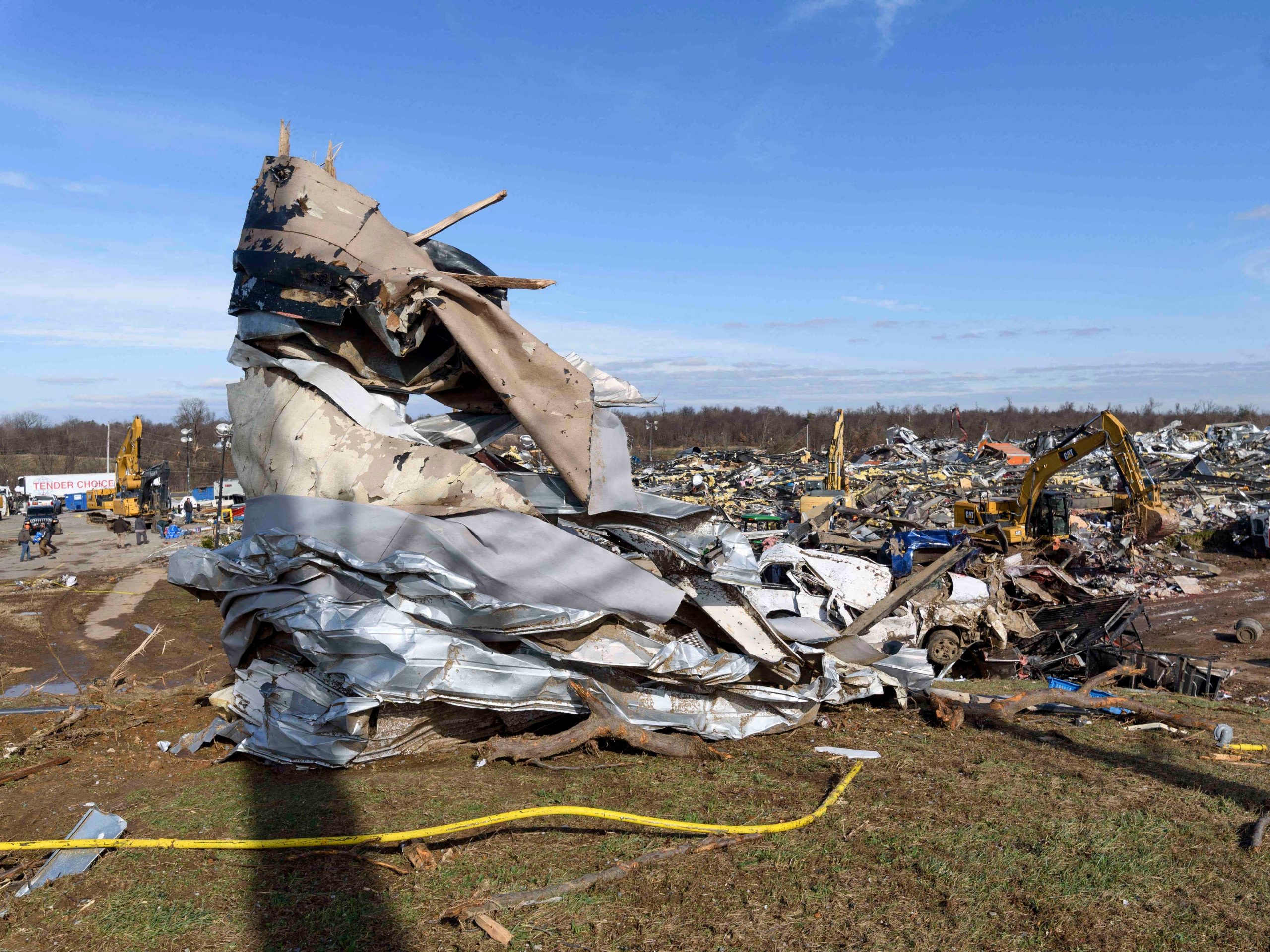 Mangled building material is wrapped around a tree on a hill overlooking search and rescue efforts at the Mayfield Consumer Products Candle Factory after it was destroyed by a tornado with workers inside, in Mayfield, Kentucky, on December 11, 2021.