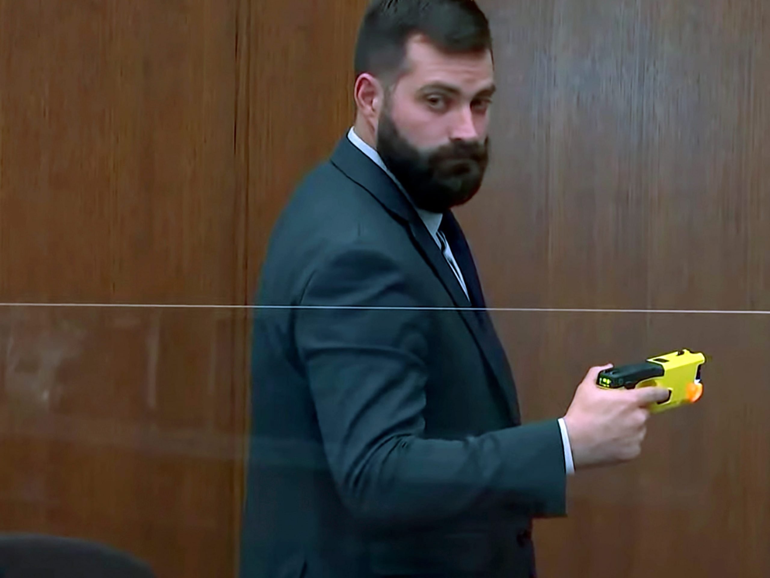 Sam McGinnis, senior special agent with the Minnesota Bureau of Criminal Apprehension, holds the taser of Brooklyn Center police Officer Kim Potter as he testifies while Hennepin County Judge Regina Chu presides over court Monday, Dec. 13, 2021, in the trial of Potter in the April 11, 2021, death of Daunte Wright, at the Hennepin County Courthouse in Minneapolis.