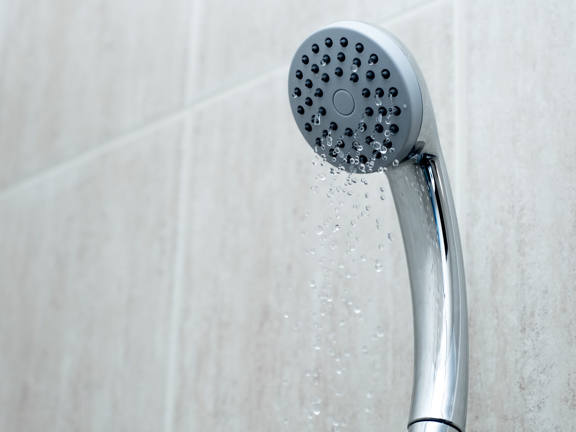 A shower head with barely any water trickling out