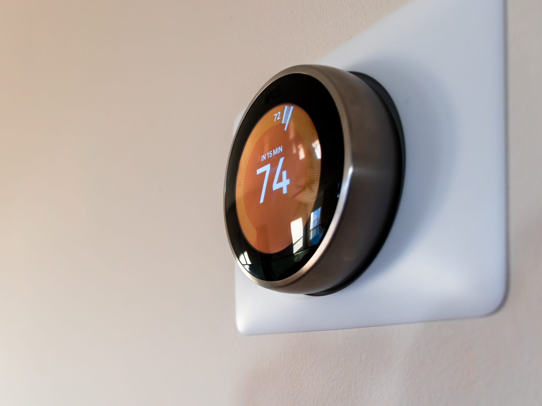 A closeup of a smart nest thermostat programmed to heat to 74 degrees