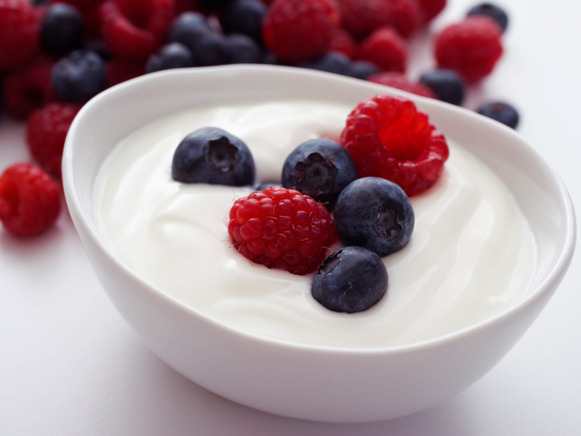 A bowl of plain yogurt topped with blueberries and raspberries