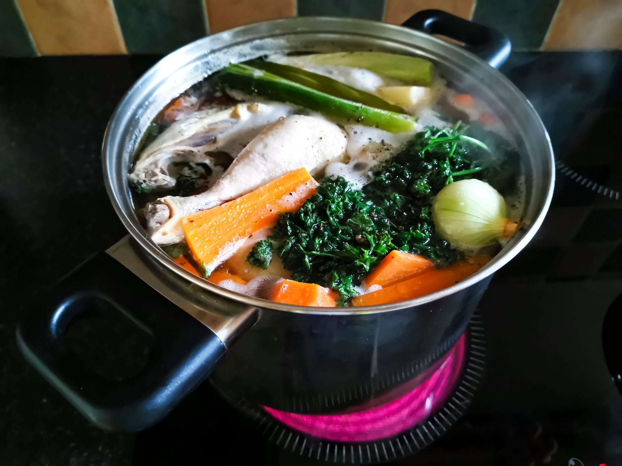 Saucepan of chicken surrounded by vegetables.