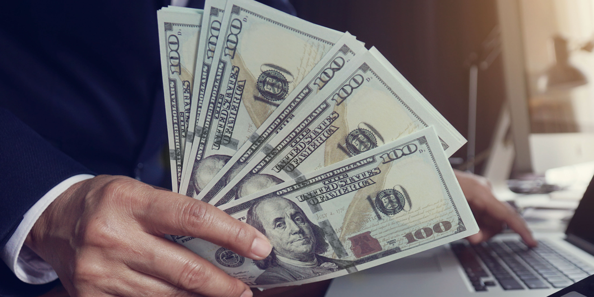 Photo of a businessman holding 100-dollar bills.