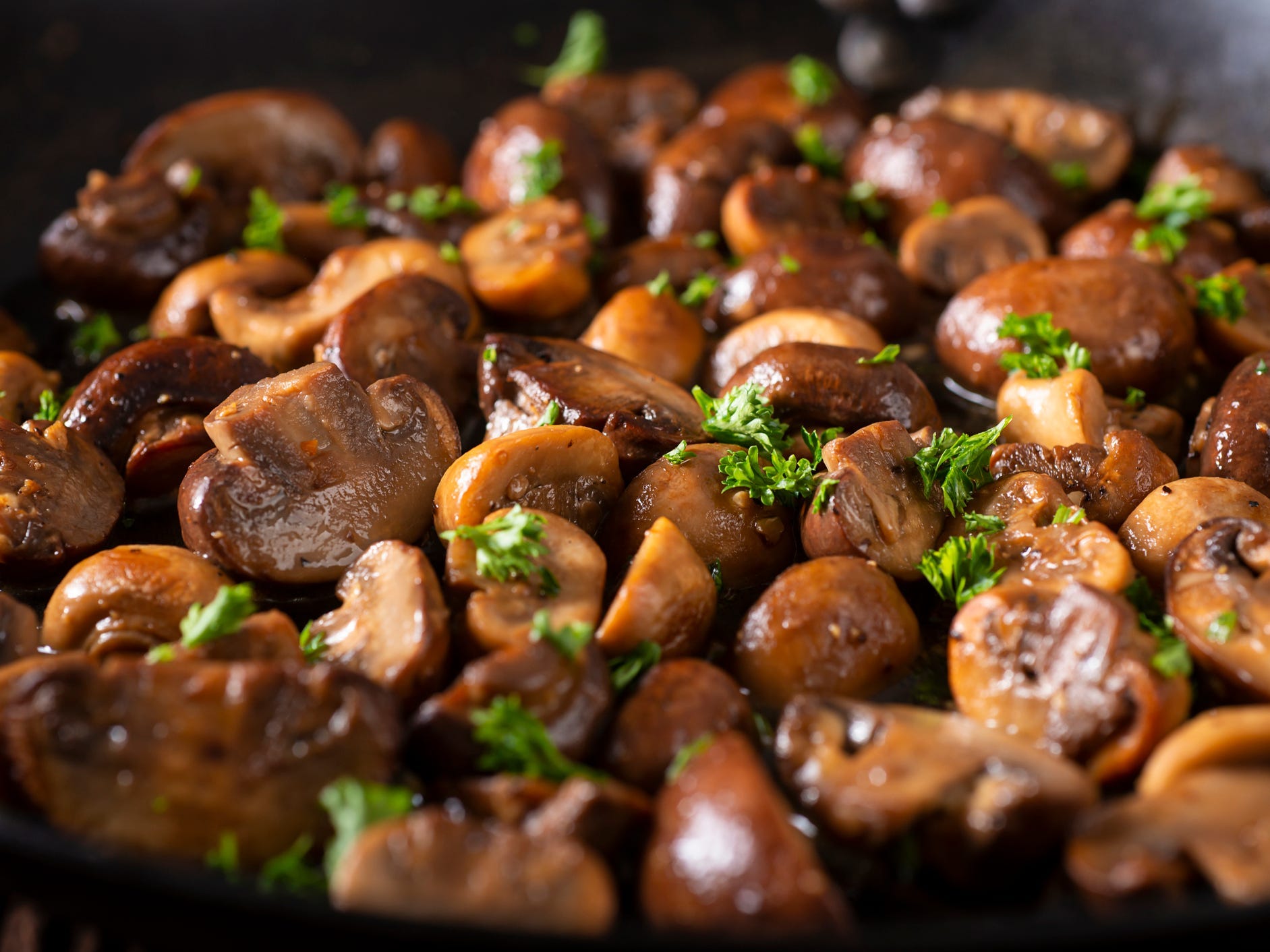 Close-up of mushrooms sautéed in a carbon steel skillet.