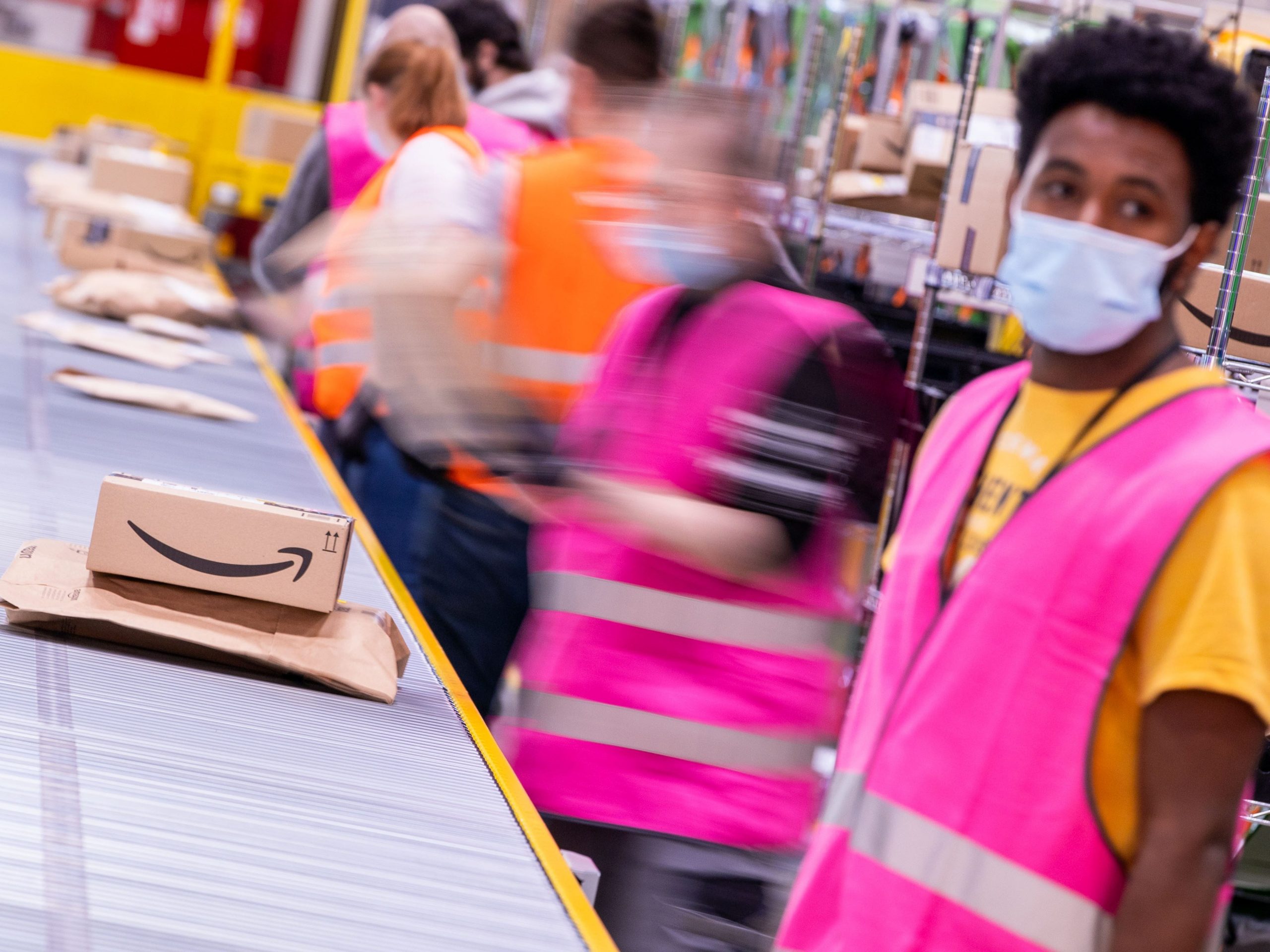 An amazon warehouse worker in line at a conveyor belt