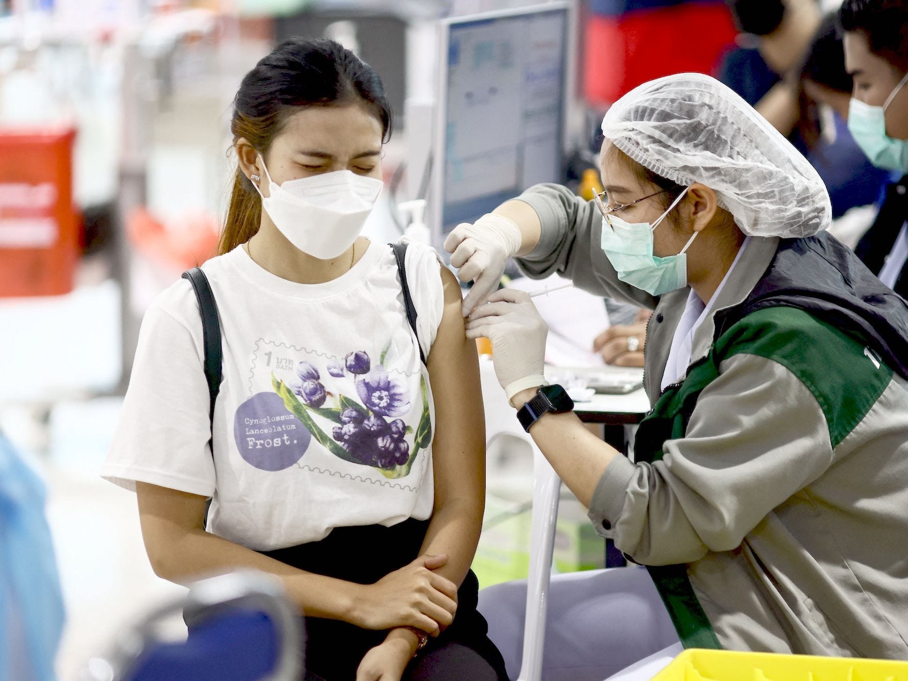 A woman wearing a mask winges as she gets a COVID-19 vaccine in Bangkok, Thailand, on December 15, 2021