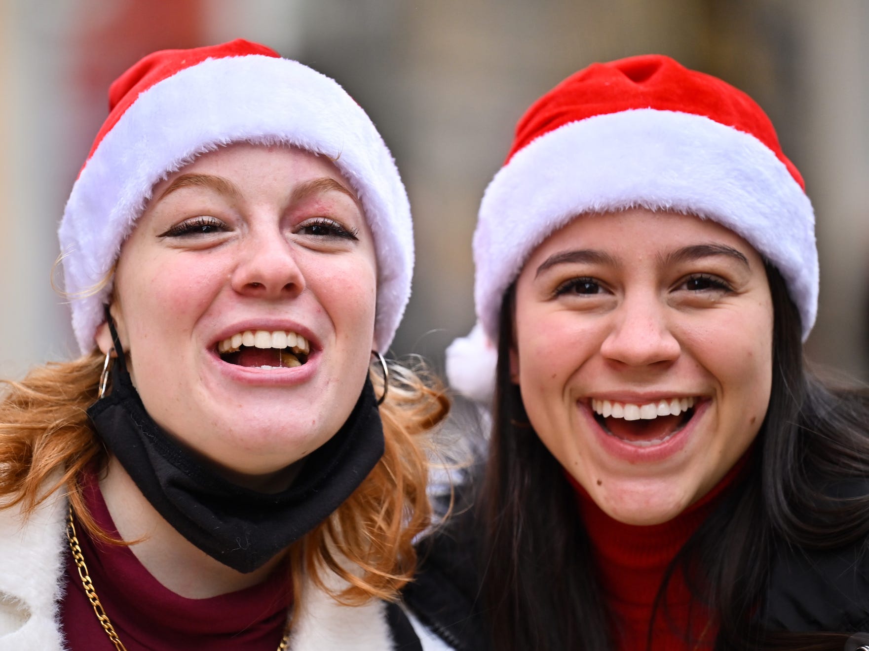 Two women wearing christmas hats smile at the camera, one wearing her mask under her chin,December 15, 2021 in Glasgow, Scotland.