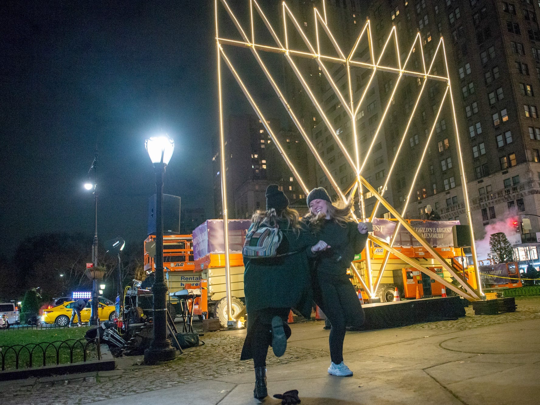 Two women dance in front of the "world's largest" Hanukkah Menorah in New York City