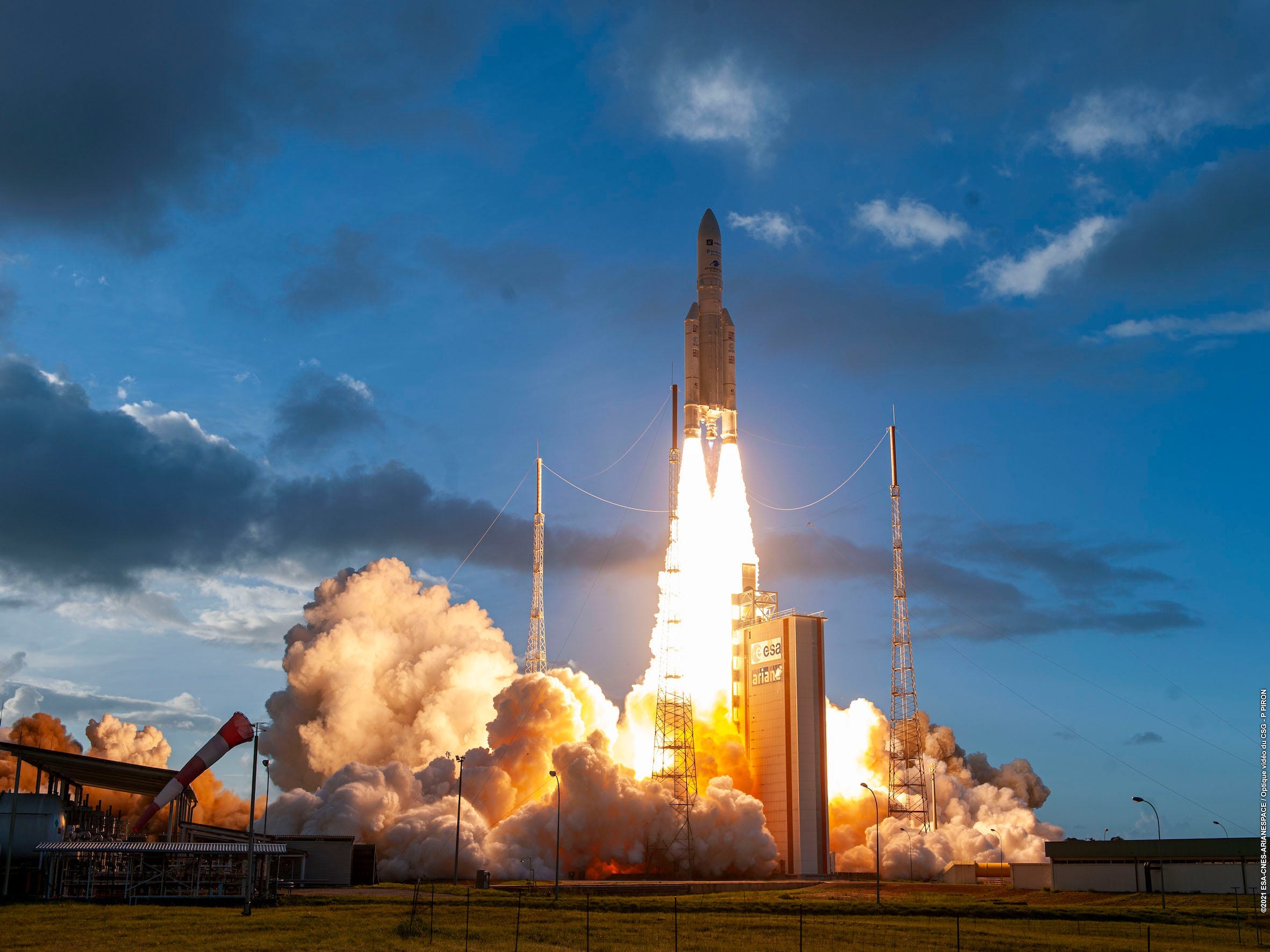 ariane 5 rocket lifting off spewing fire and smoke against dark blue sky