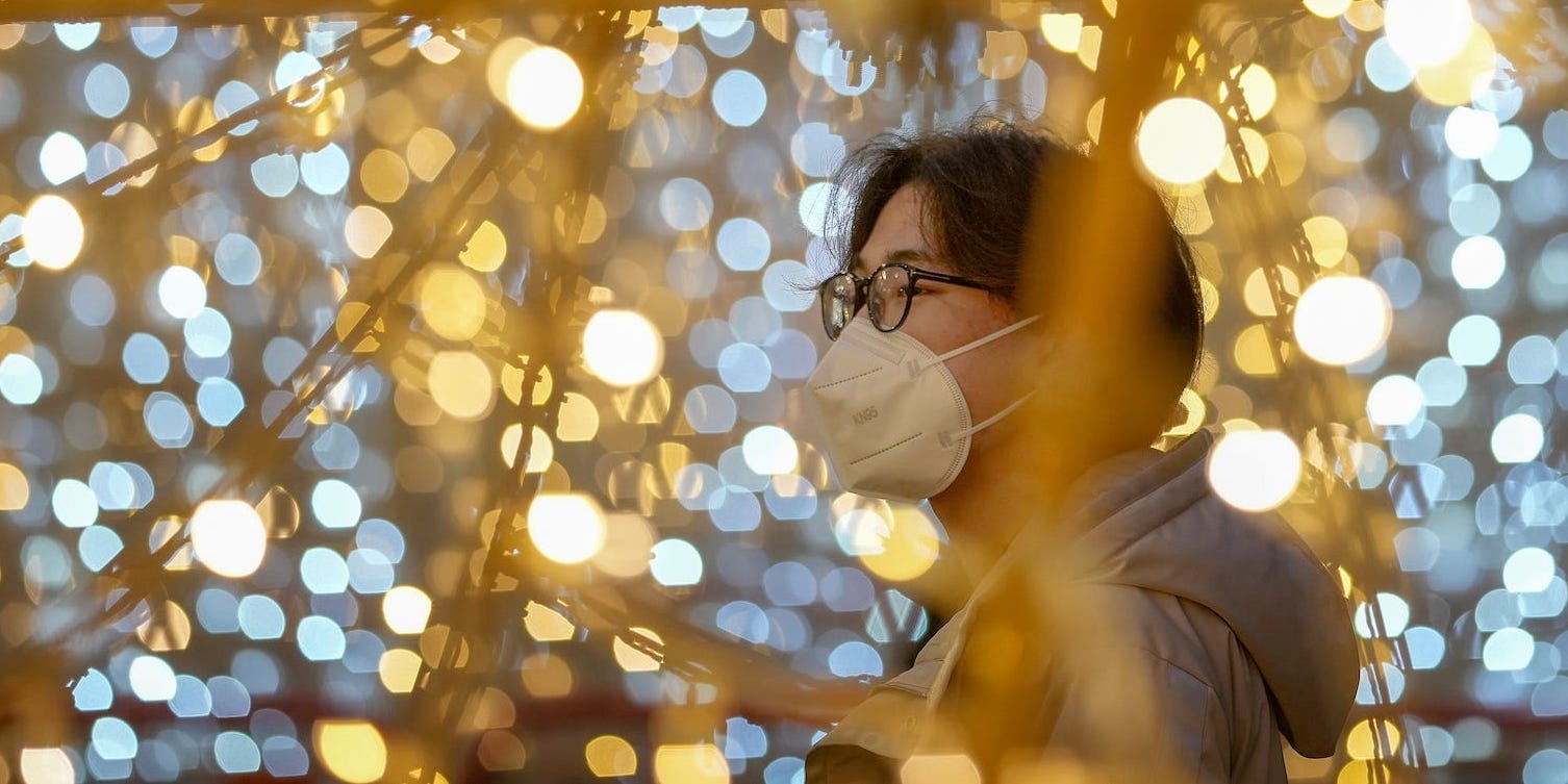 A person wearing a mask is pictured amongst twinkle lights on December 14, 2021 in Manchester, England.