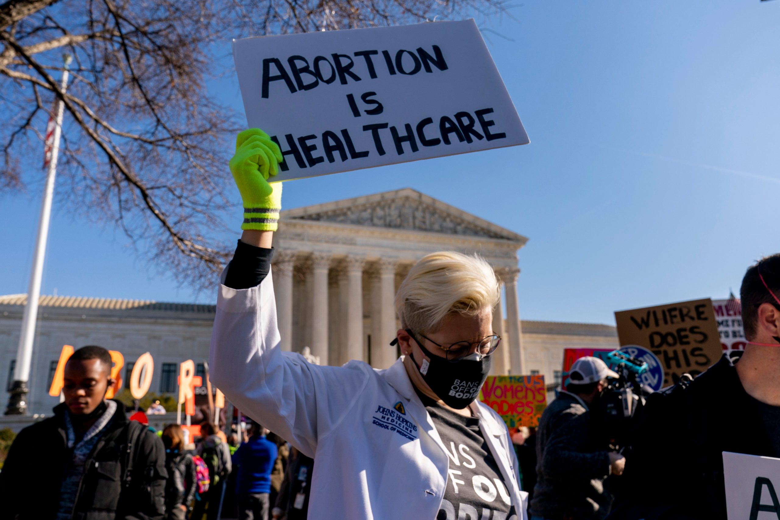 A woman holds a poster that reads "Abortion is Healthcare" as abortion rights advocates and anti-abortion protesters demonstrate in front of the U.S. Supreme Court, Dec. 1, 2021, in Washington, as the court hears arguments in a case from Mississippi, where a 2018 law would ban abortions after 15 weeks of pregnancy, well before viability.