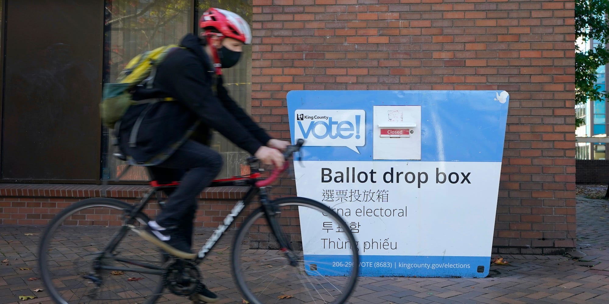 A cyclist rides past a ballot drop box, Tuesday, Oct. 13, 2020, in Seattle