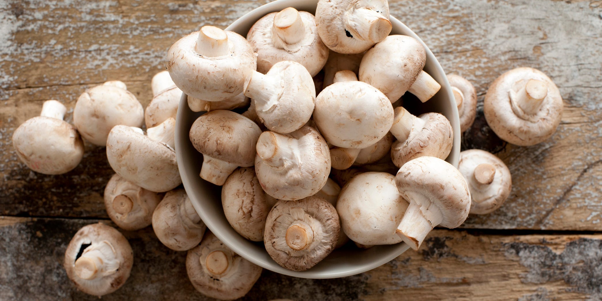 An overflowing bowl of white button mushrooms