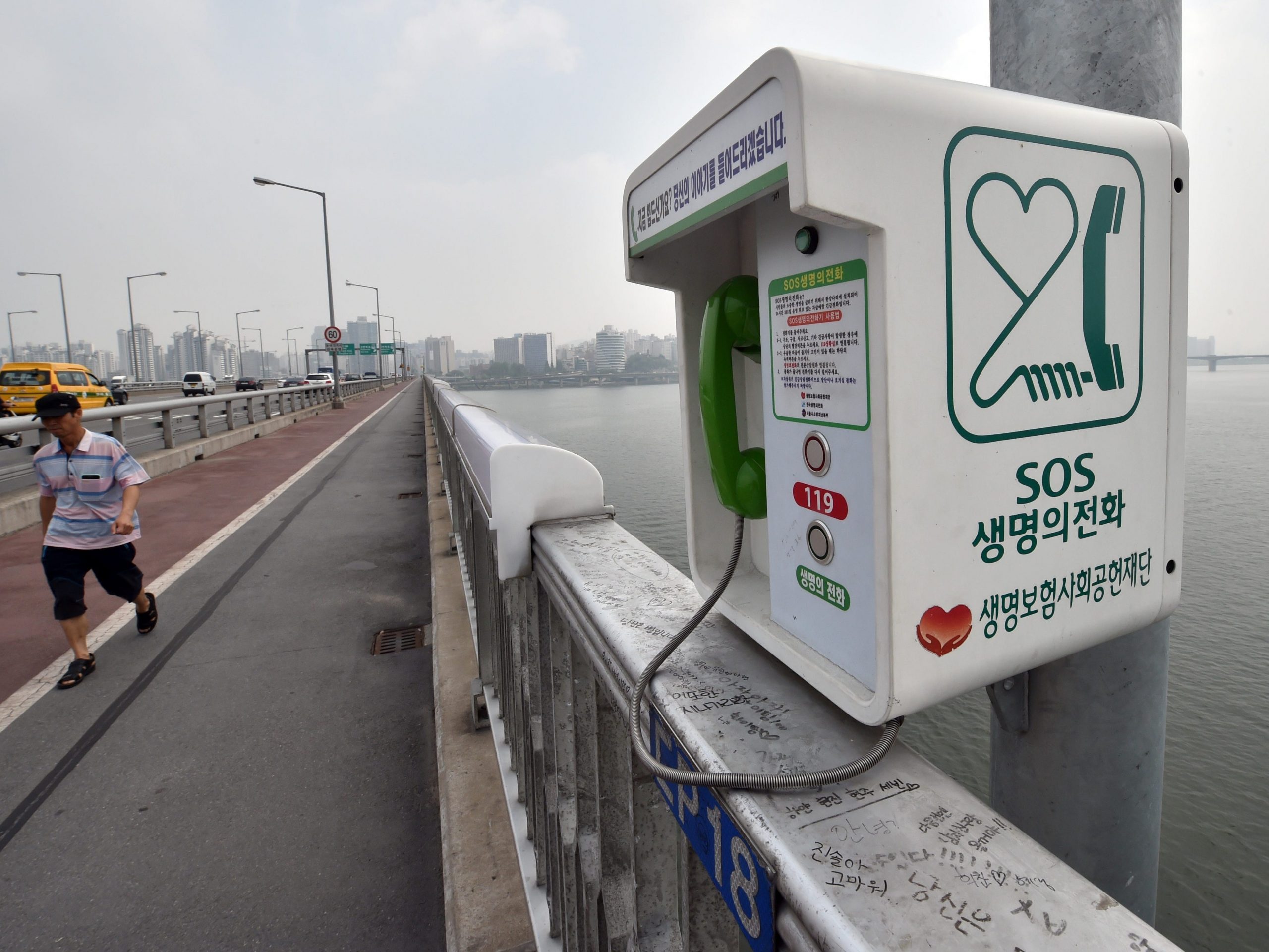 A man walks past an emergency telephone on Mapo Bridge, a common site for suicides, over the Han river in Seoul on July 14, 2014.
