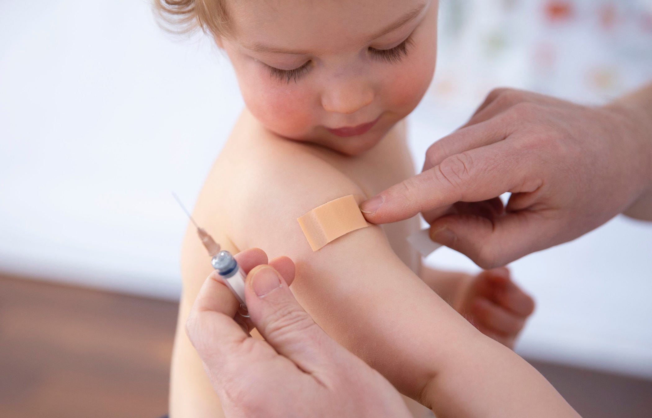 a baby looking at their band aid after being given a vaccine injection