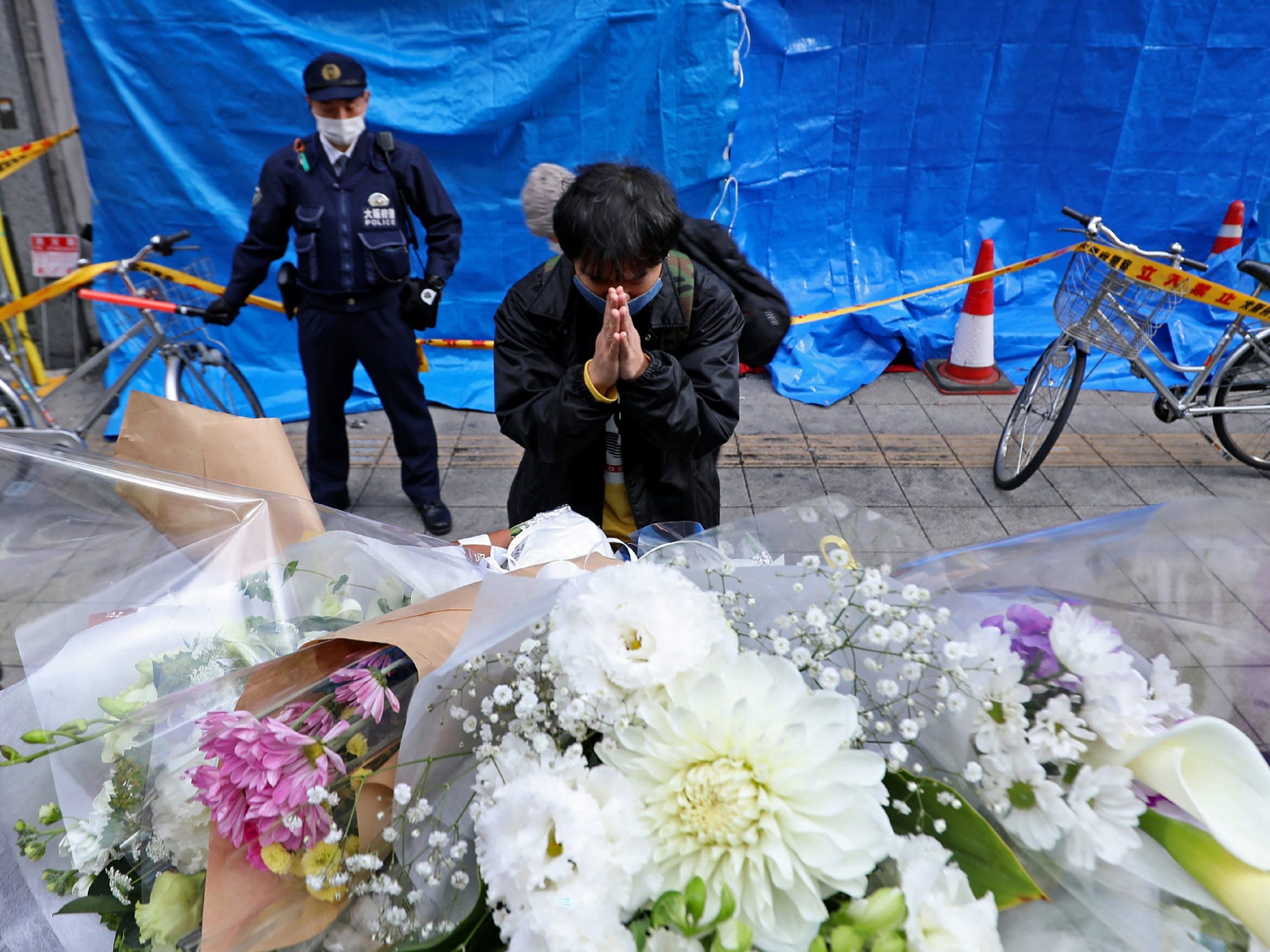 A man prays for victims in front of an office building, where a fire broke out the previous day, in Osaka on December 18, 2021.