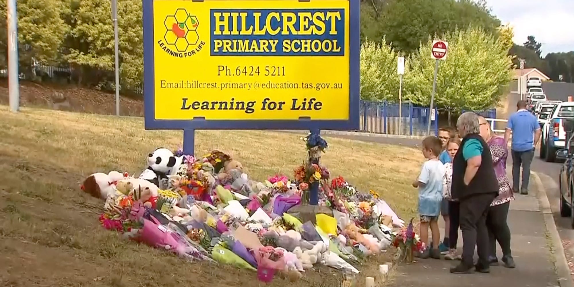 In this image made from video, people lay flowers at a makeshift memorial outside the Hillcrest Primary School in Devonport, Tasmania, Australia, Friday, Dec. 17, 2021.