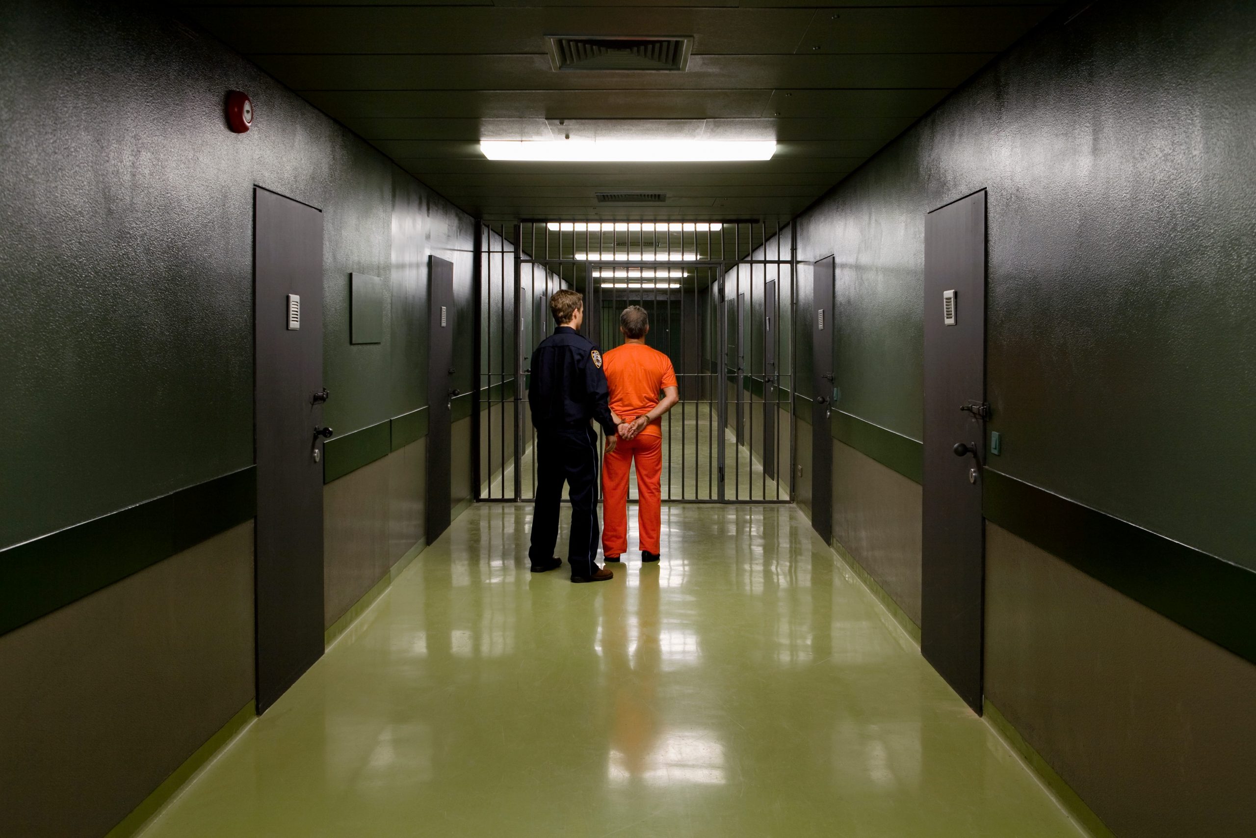 A prison guard leading a prisoner along a corridor